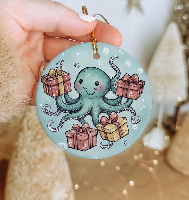 a hand holding a christmas ornament with an octopus holding presents