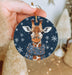a hand holding a christmas ornament with a picture of a giraffe