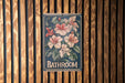 a bathroom sign hanging on a wooden wall