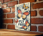 a sign that says fly free on a brick wall