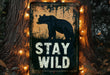 a sign that says stay wild in front of a tree