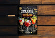a sign advertising cocktails on a wooden bench