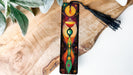 a wooden piece of art with a tassel hanging from it
