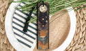 a bookmark on a plate next to a plant