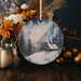 a christmas ornament with a picture of a house in the snow