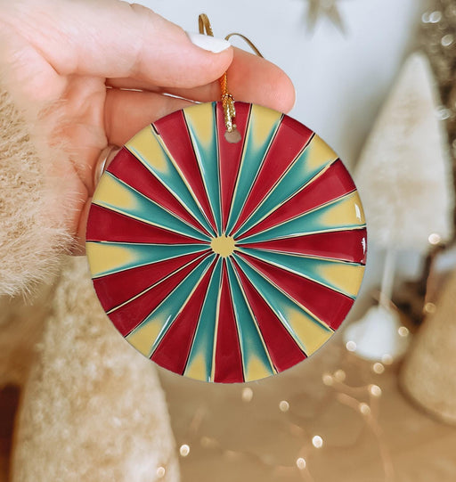a hand holding a red, yellow and blue ornament