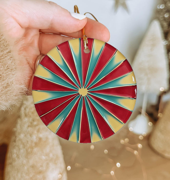 a hand holding a red, yellow and blue ornament