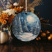 a christmas ornament with a snowy scene on it