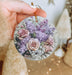 a person holding a round ornament with flowers on it