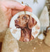 a hand holding a christmas ornament with a picture of a dog on it