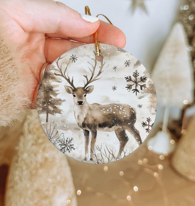 a hand holding a christmas ornament with a deer on it