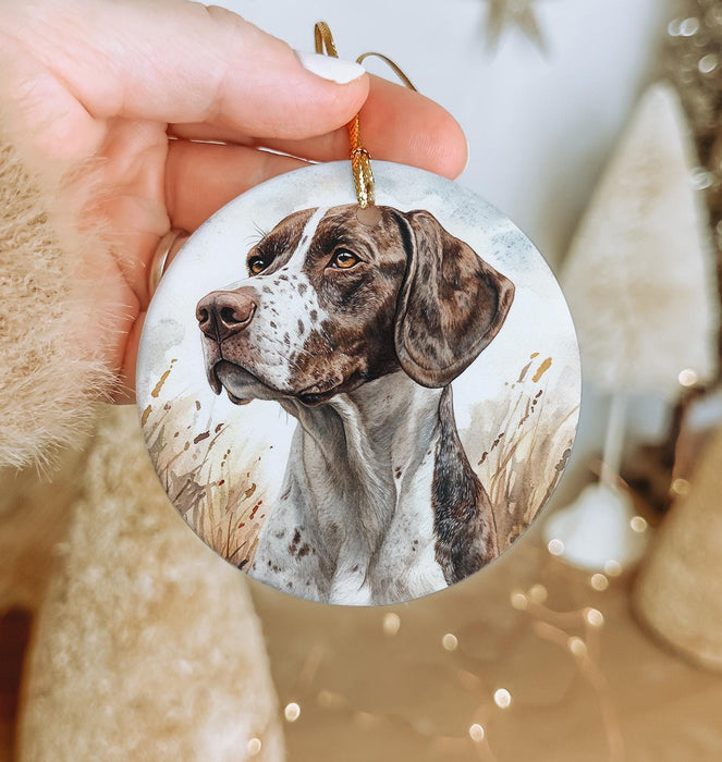 a hand holding a christmas ornament with a dog on it