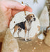 a hand holding a christmas ornament with a dog on it