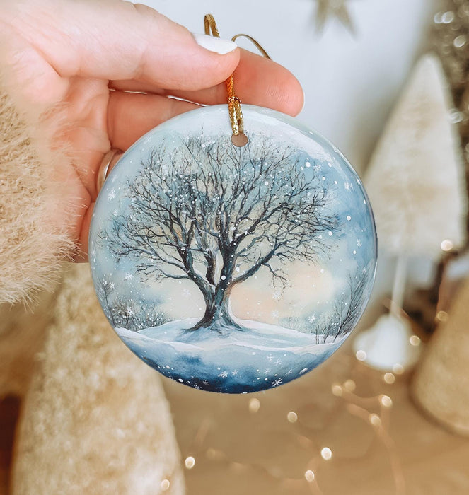 a hand holding a glass ornament with a tree on it