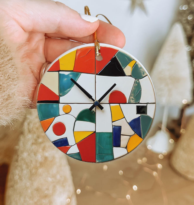 a hand holding a colorful clock on a christmas ornament
