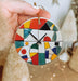 a hand holding a colorful clock on a christmas ornament
