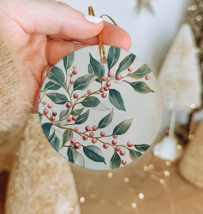 a hand holding a christmas ornament with berries on it
