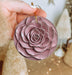 a person holding a pink flower ornament in their hand
