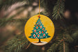 a ceramic christmas tree ornament hanging from a pine tree