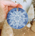 a hand holding a blue and white ornament