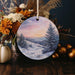 a christmas ornament with a painting of a snowy landscape