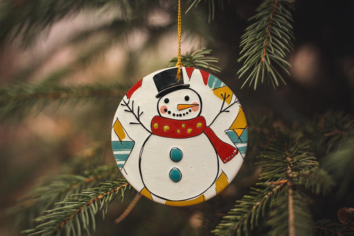 a snowman ornament hanging from a christmas tree