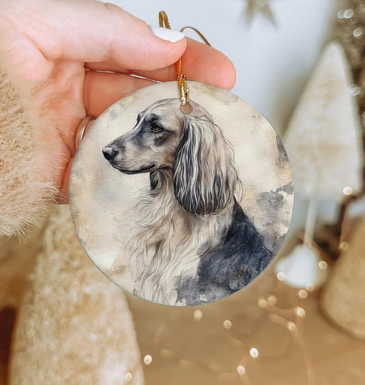 a hand holding a christmas ornament with a dog on it