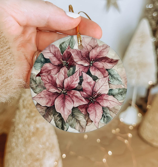 a hand holding a christmas ornament with flowers on it