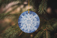 a blue and white ornament hanging from a tree