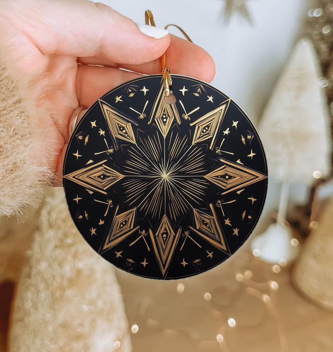 a hand holding a black and gold ornament