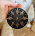 a hand holding a black and gold ornament