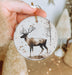 a hand holding a christmas ornament with a deer on it