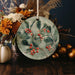 a ceramic ornament decorated with berries and leaves