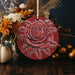 a red ornament with a flower on it