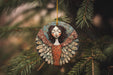 a ceramic angel ornament hanging from a christmas tree