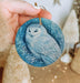 a hand holding an ornament with an owl on it