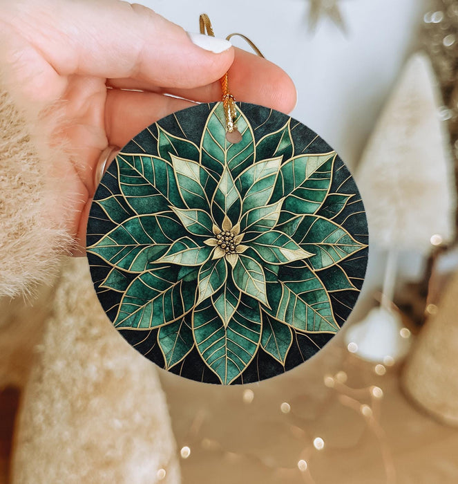 a hand holding a christmas ornament with a green flower on it