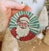 a person holding a christmas ornament with a santa clause on it