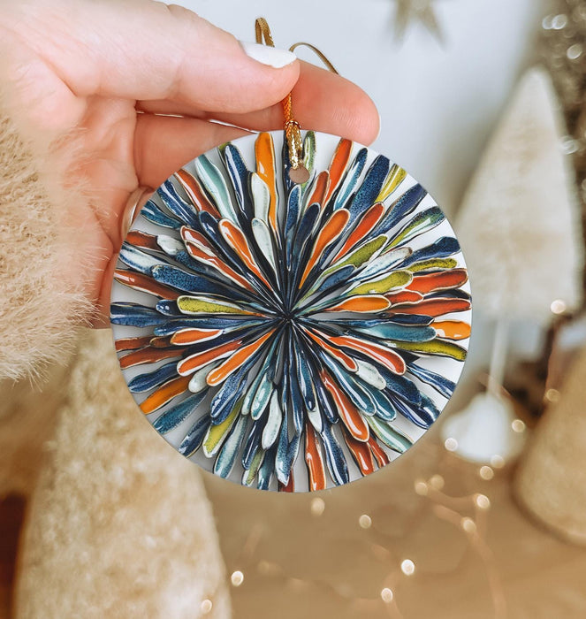 a hand holding a glass ornament in front of a christmas tree