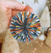 a hand holding a glass ornament in front of a christmas tree
