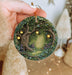 a hand holding a christmas ornament with a tree