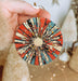 a hand holding a red, white, and blue ornament