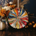 a plate with a colorful design on it next to a vase of flowers