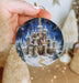 a hand holding a christmas ornament with a castle on it