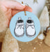 a hand holding a blue ornament with a pair of shoes on it