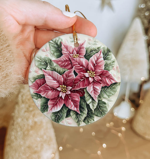 a hand holding a christmas ornament with flowers on it