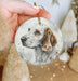 a hand holding a white and brown dog ornament