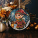 a christmas ornament with a picture of a girl holding a lantern