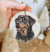 a hand holding a christmas ornament with a picture of a dog