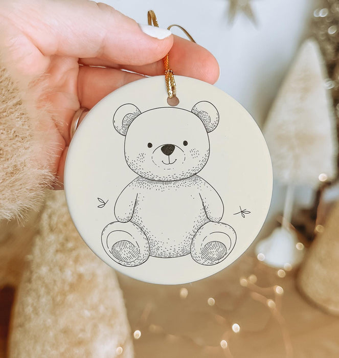 a hand holding a christmas ornament with a teddy bear on it
